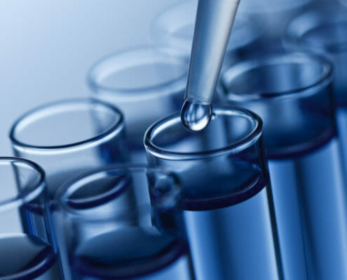 A close-up image of a liquid being added to a test tube with a dropper